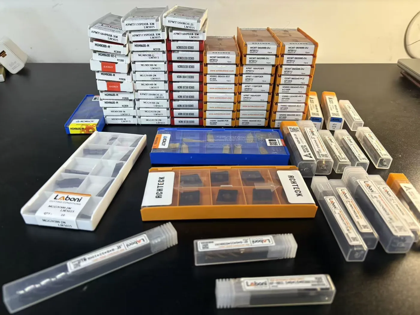 Indexable insert boxes from several brands laid out on a workbench